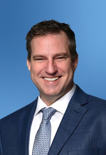 A smiling man wearing a suit and tie, representing a legal AI software company, against a blue background.