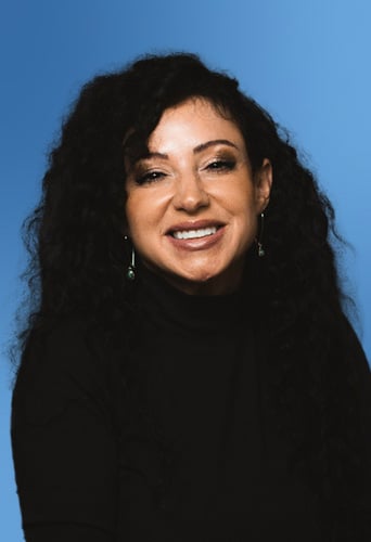 Woman with curly hair smiling against a blue background, reminiscent of the interface colors often used in legal project management software.