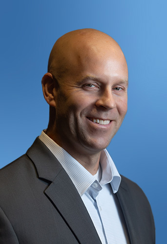 Bald man in a suit smiling against a blue background with law firm software.